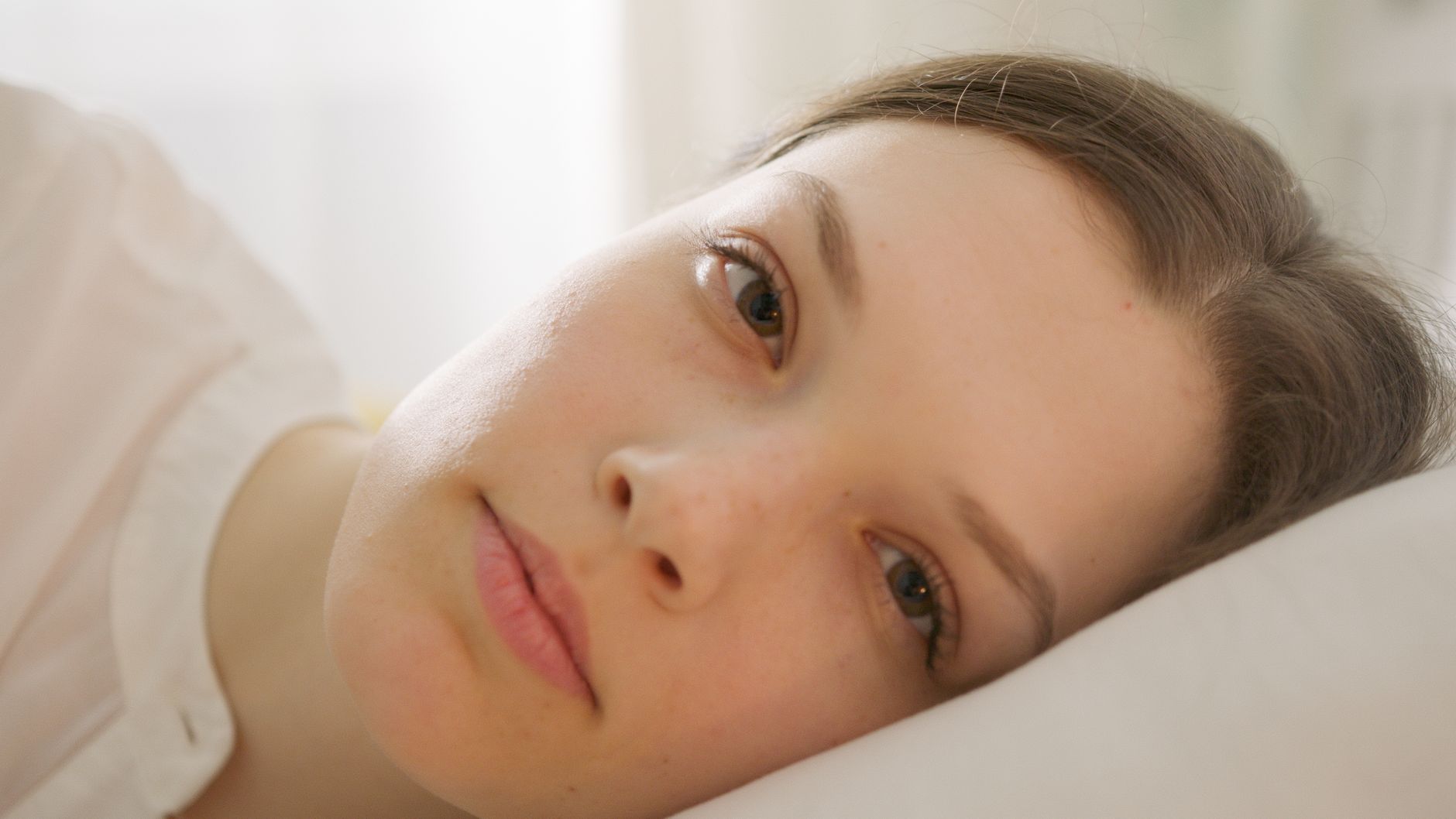 Portrait of a relaxed woman lying in bed with soft lighting.