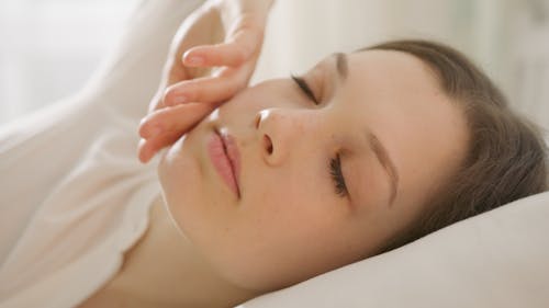 Photo of a Woman Touching Her Face while Her Eyes are Closed