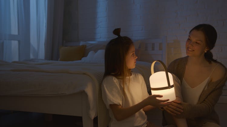 A Girl Holding A Light Near Her Mother