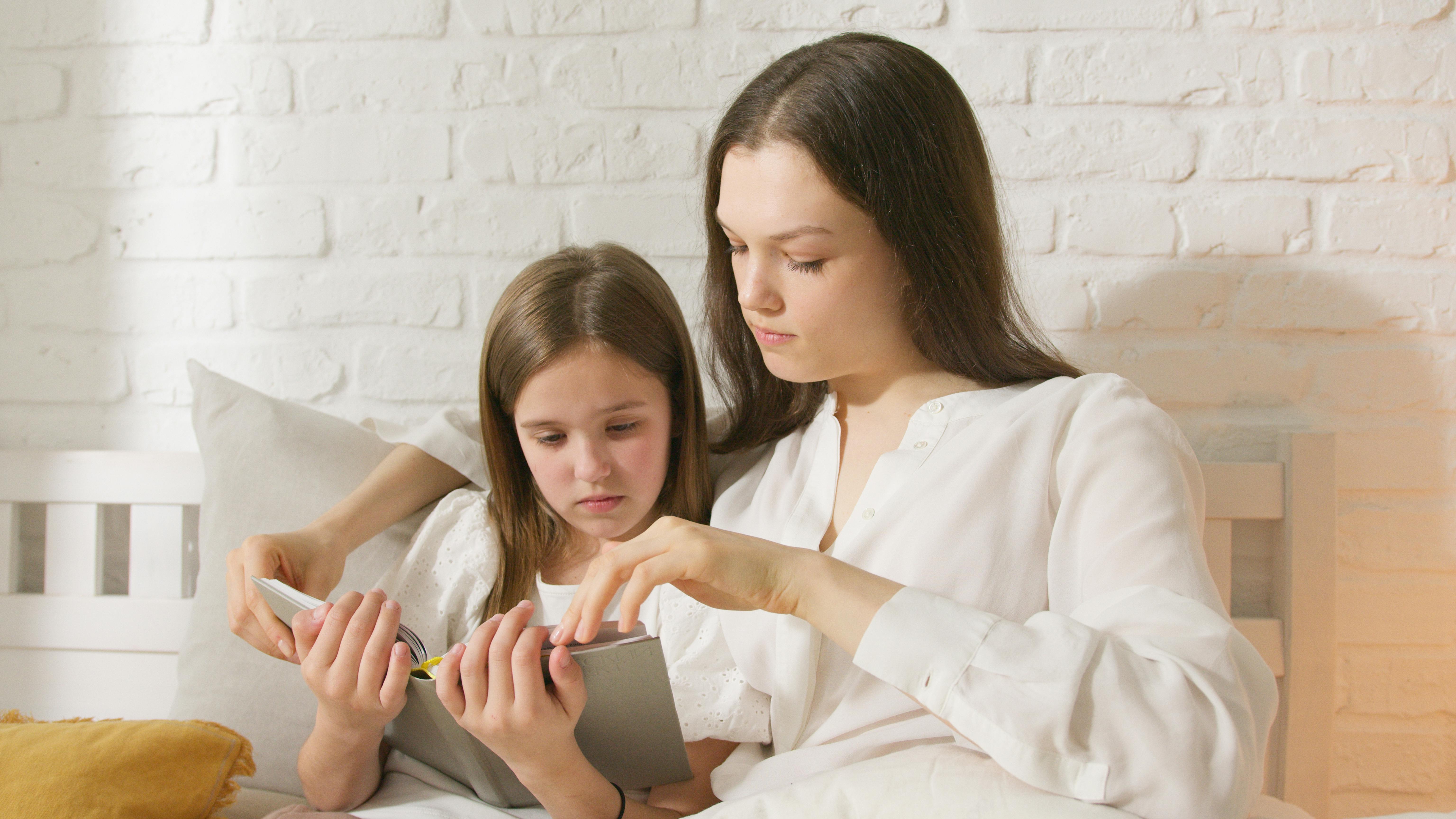 a kid and her mother reading a book tgoeteher