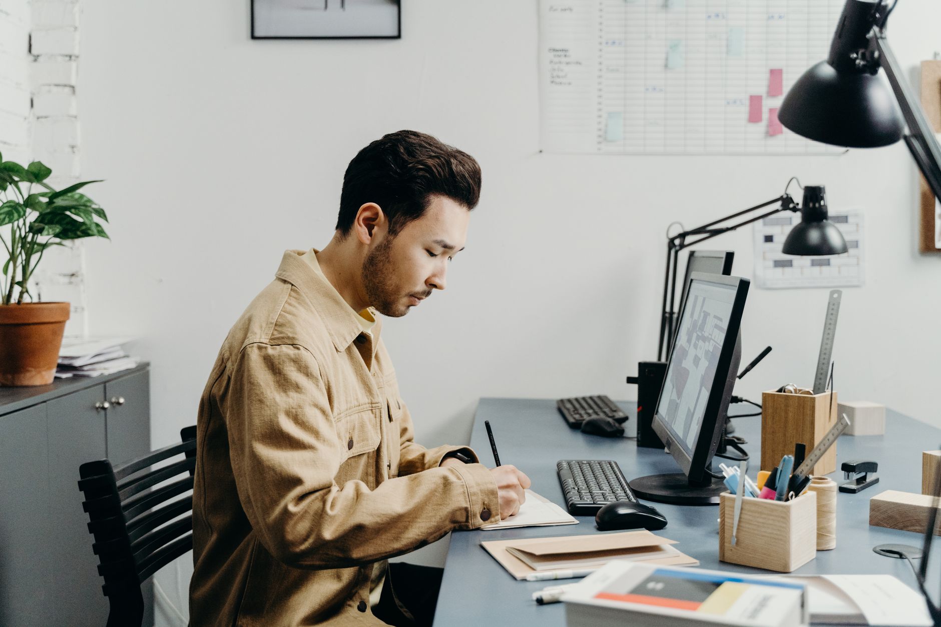 Young man concentrating on work at a modern office desk with books and computer.