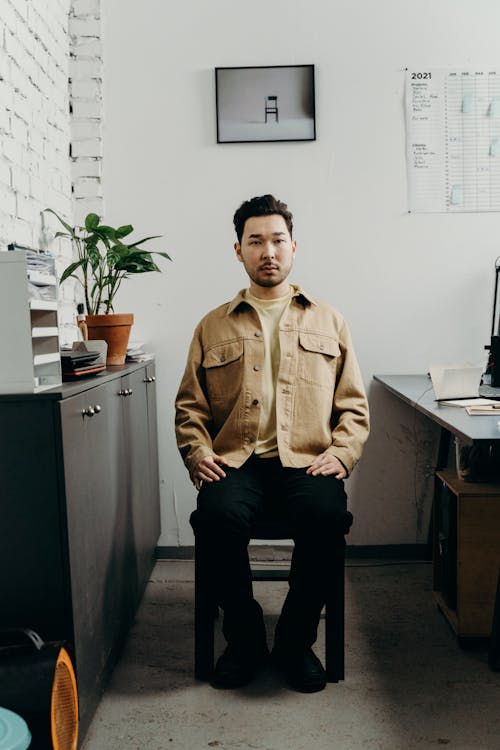 Man in Brown Jacket Sitting on Chair in Office · Free Stock Photo
