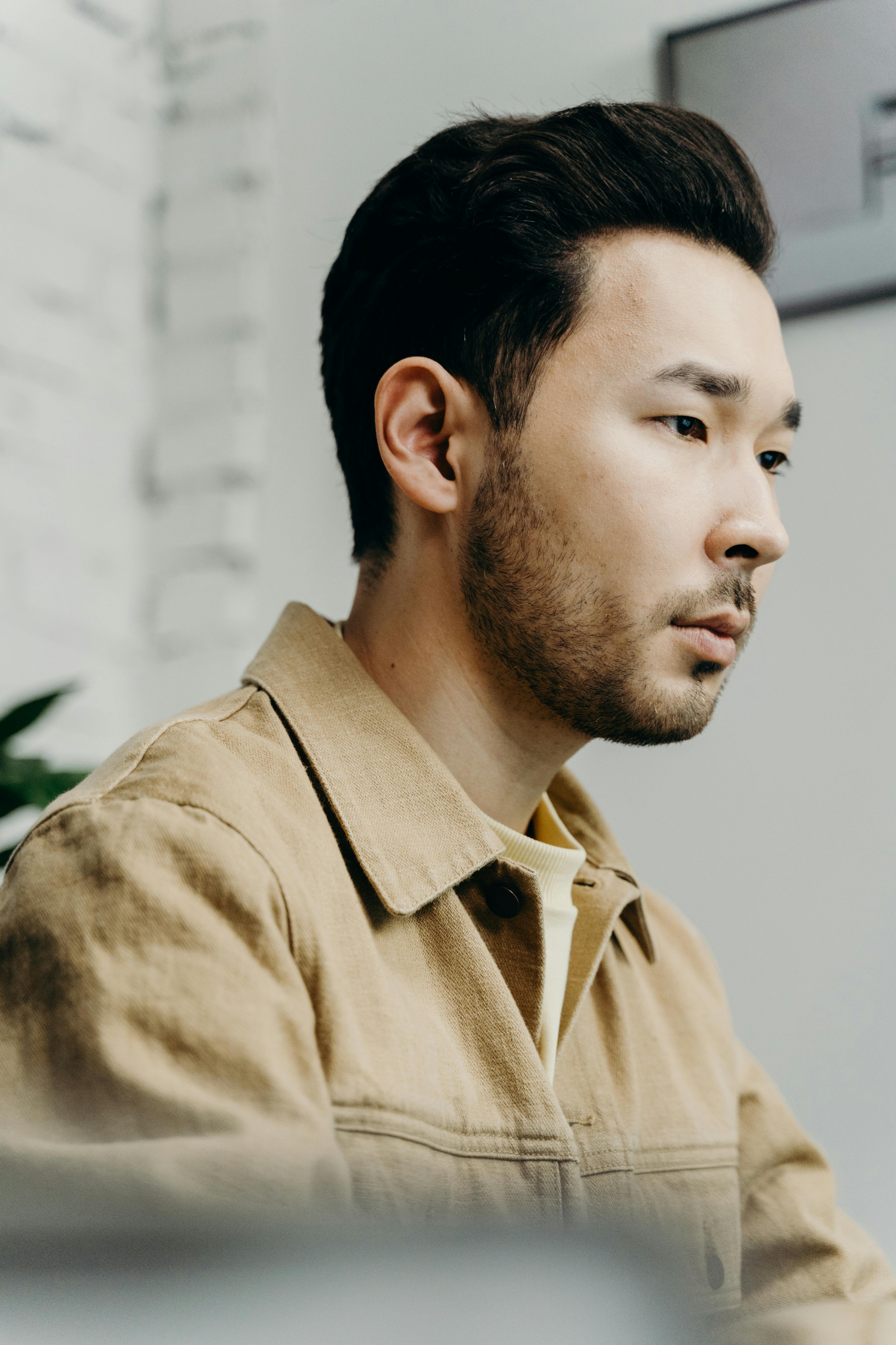 Close-up portrait of a young man with stubble, focused indoors.