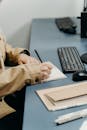 Photo of a Person's Hands Writing with a Black Pen