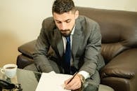 Man in Gray Suit Jacket Sitting on Black Leather Couch