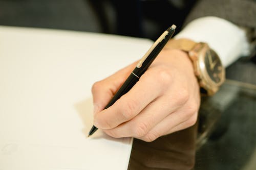 Close-Up Shot of a Person Writing on White Paper Using a Pen