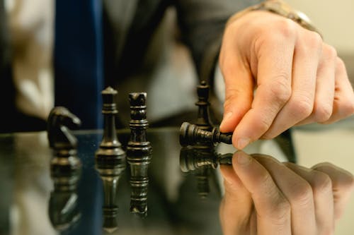 A Person's Hand Touching a Black Chess Piece
