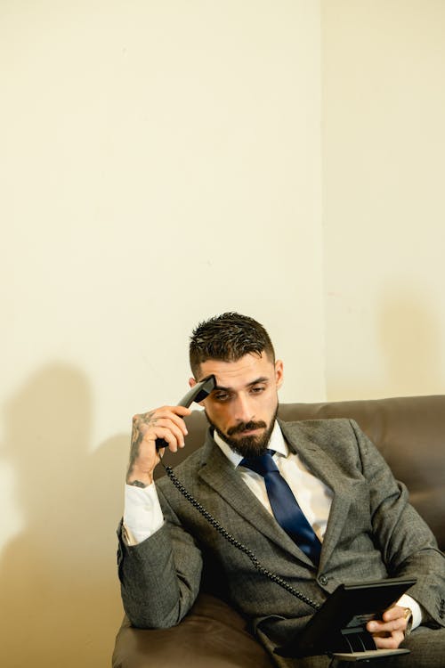 Man in Gray Suit Jacket Holding a Telephone