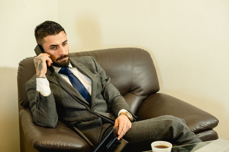 Bearded man in gray suit talking on the phone while seated in a modern office