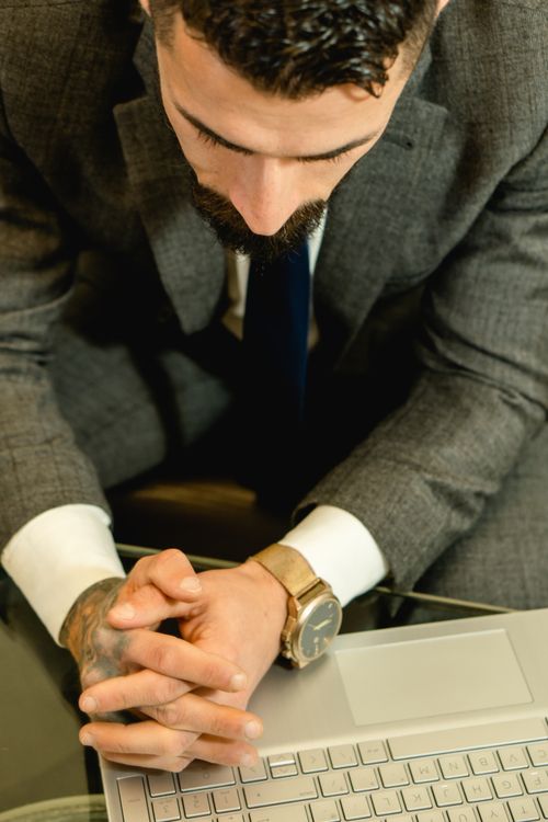 Free A focused businessman in a gray suit working on a laptop at his desk. Stock Photo