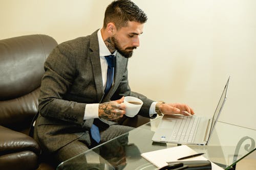 A Man in Gray Suit Using a Laptop