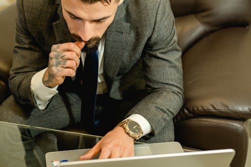 A Man in Gray Suit Jacket Sitting on a Leather Couch