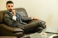 Man in Black Suit Jacket Sitting on Black Leather Couch