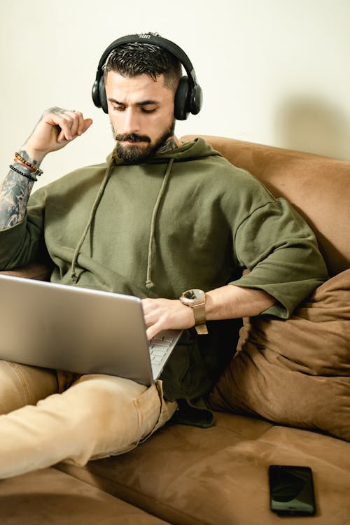 Man in Green Hoodie Sitting on a Brown Couch