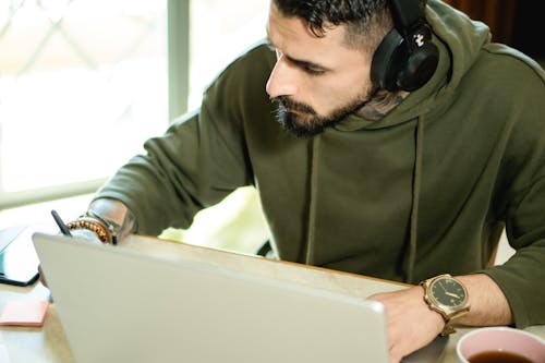 A Man in Green Long Sleeve Shirt Using a Laptop