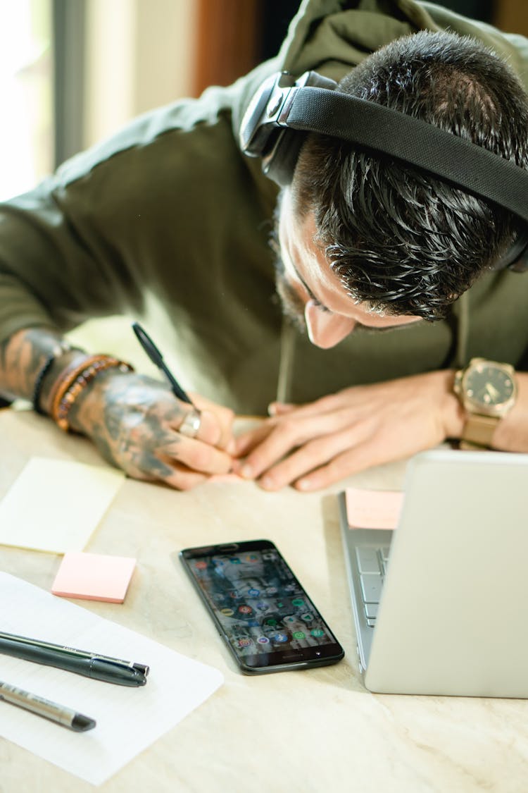 A Man With Black Headphones Writing