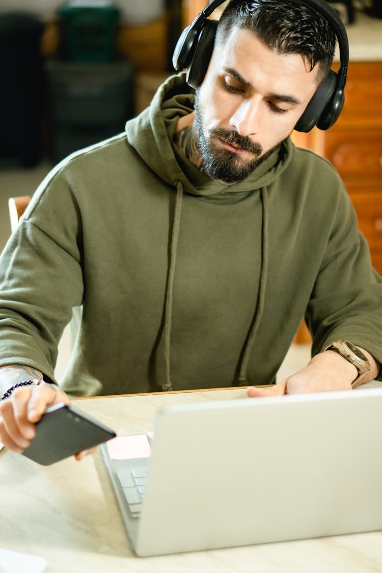 Photo Of A Man With Black Headphones Looking At His Cell Phone