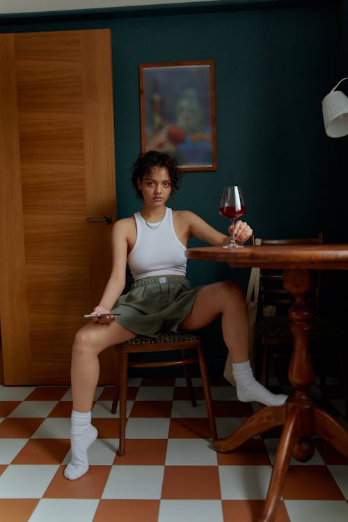 Photo of a Woman in a White Tank Top Holding a Glass of Wine