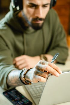 Man in hoodie working on a laptop with focus, highlighting remote work lifestyle.