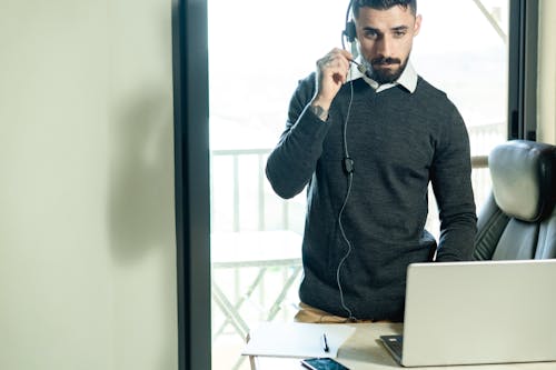 Photo of a Man Holding the Microphone of His Headset