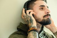 Man in Green and Brown Camouflage Jacket Wearing Black Headphones