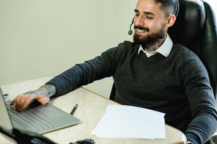 Photo Of A Man With A Headset Using His Laptop