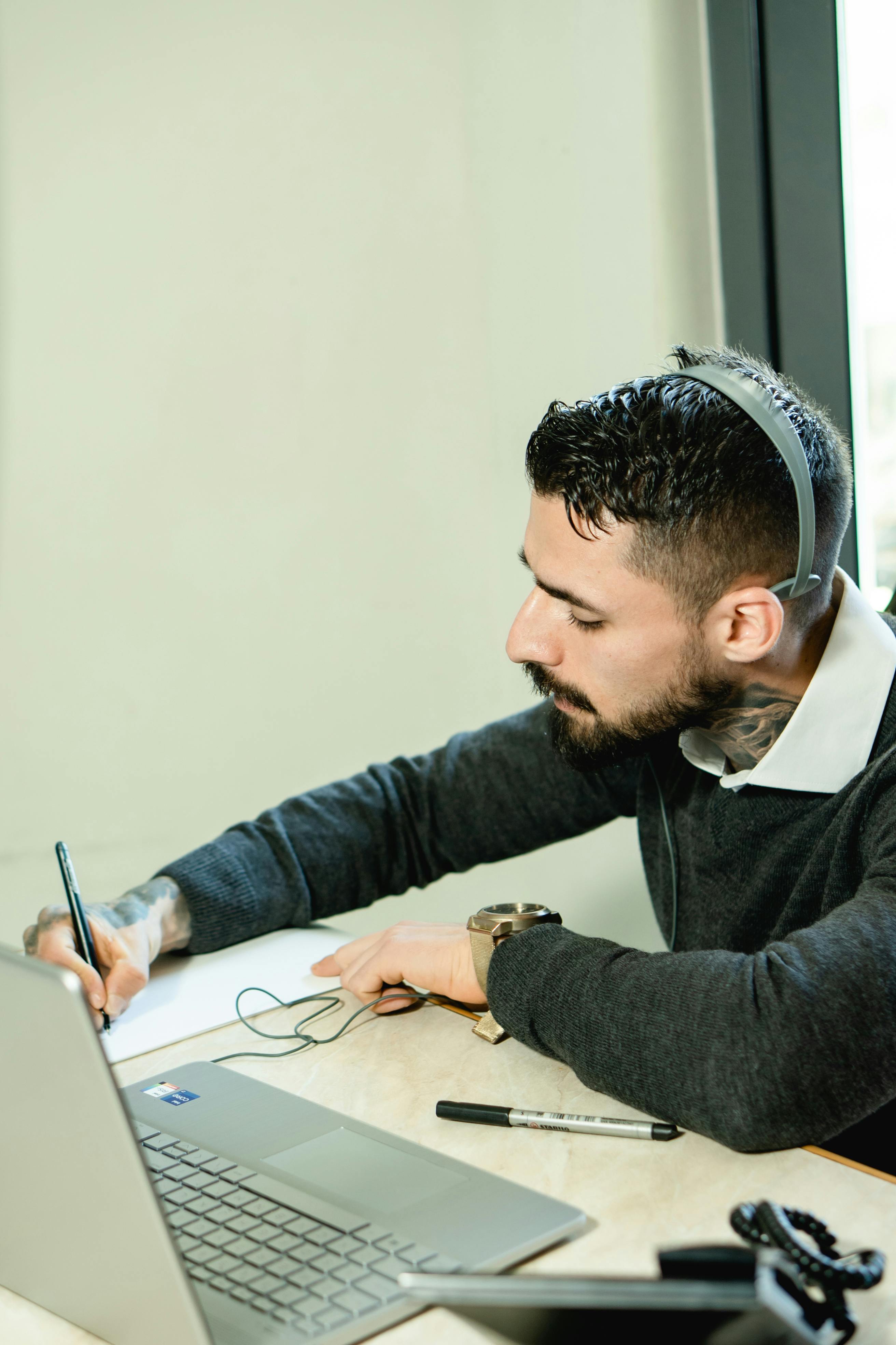 photo of a man with a headset writing on a piece of paper