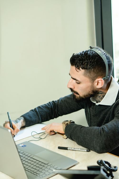 Free A man in an office using a laptop and headset, engaged in professional work. Stock Photo