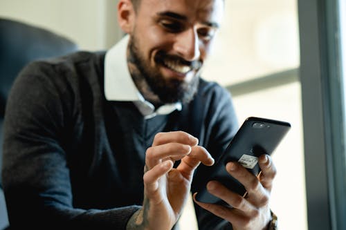 Free Smiling Man Using a Smartphone Stock Photo