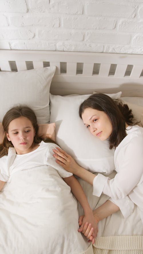 Free High-Angle Shot of a Mother and Her Daughter Lying on the Bed Stock Photo