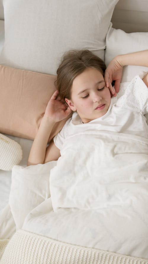 Free Young Girl in White Shirt Lying Down on Bed Stock Photo