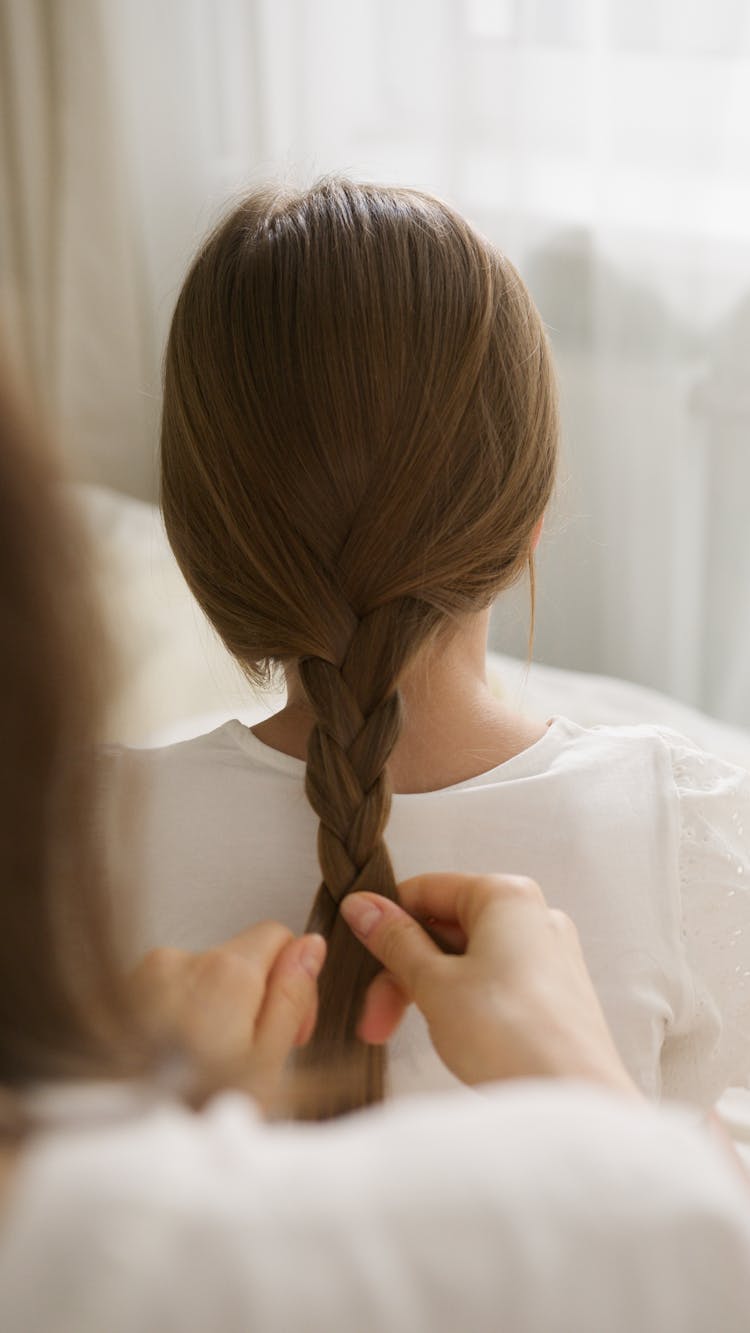 Photograph Of A Person Braiding A Girl's Hair