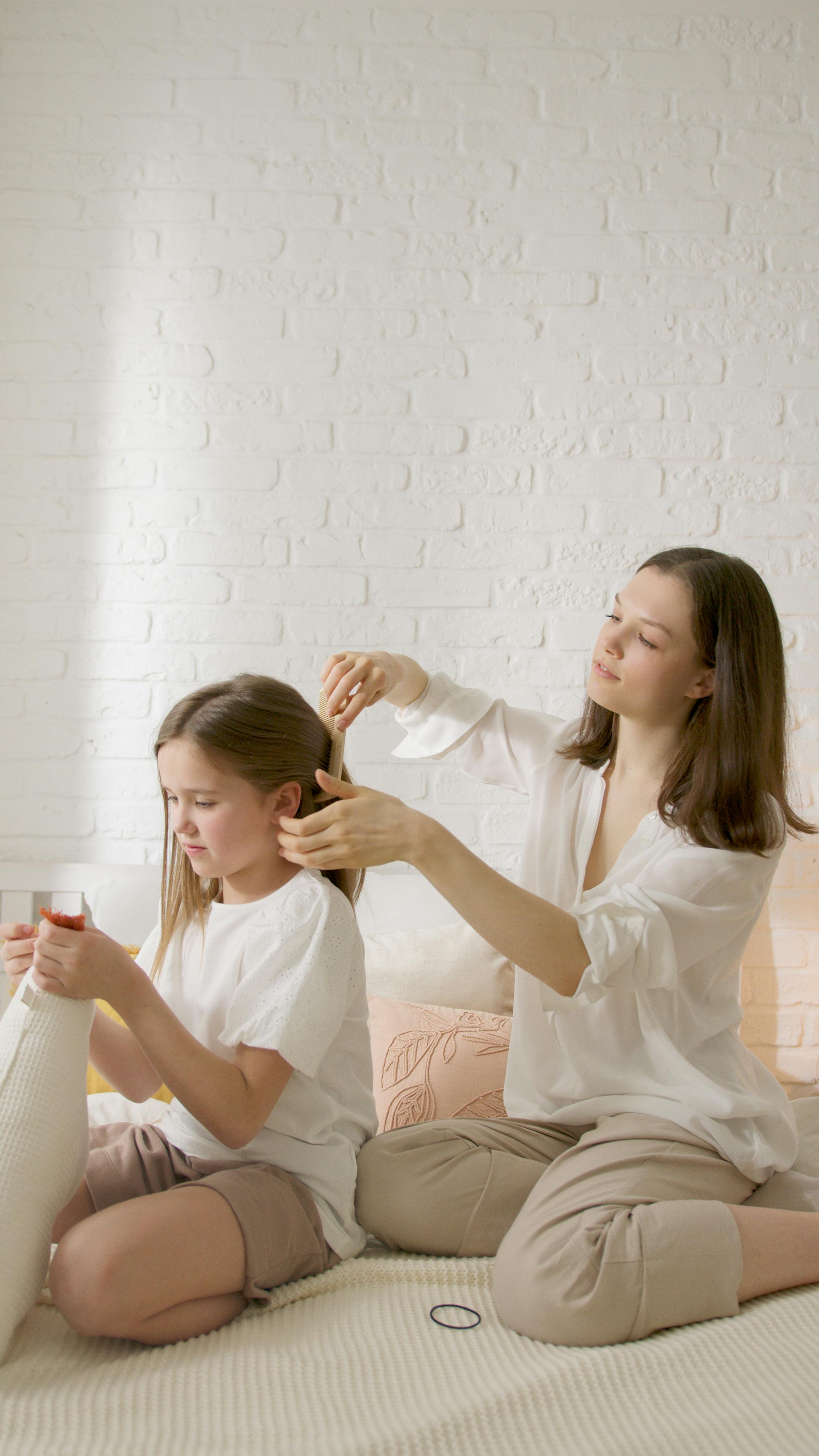 woman in white dress shirt holding girl in white dress