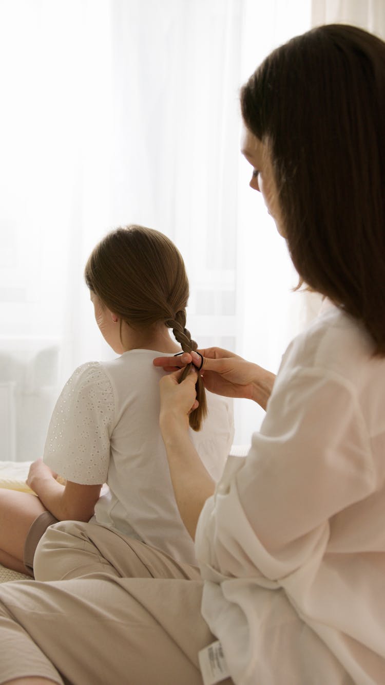 A Woman Braiding Her Daughter's Hair