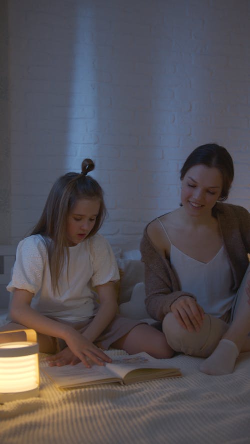 Mother and Daughter Reading a Book before Bedtime