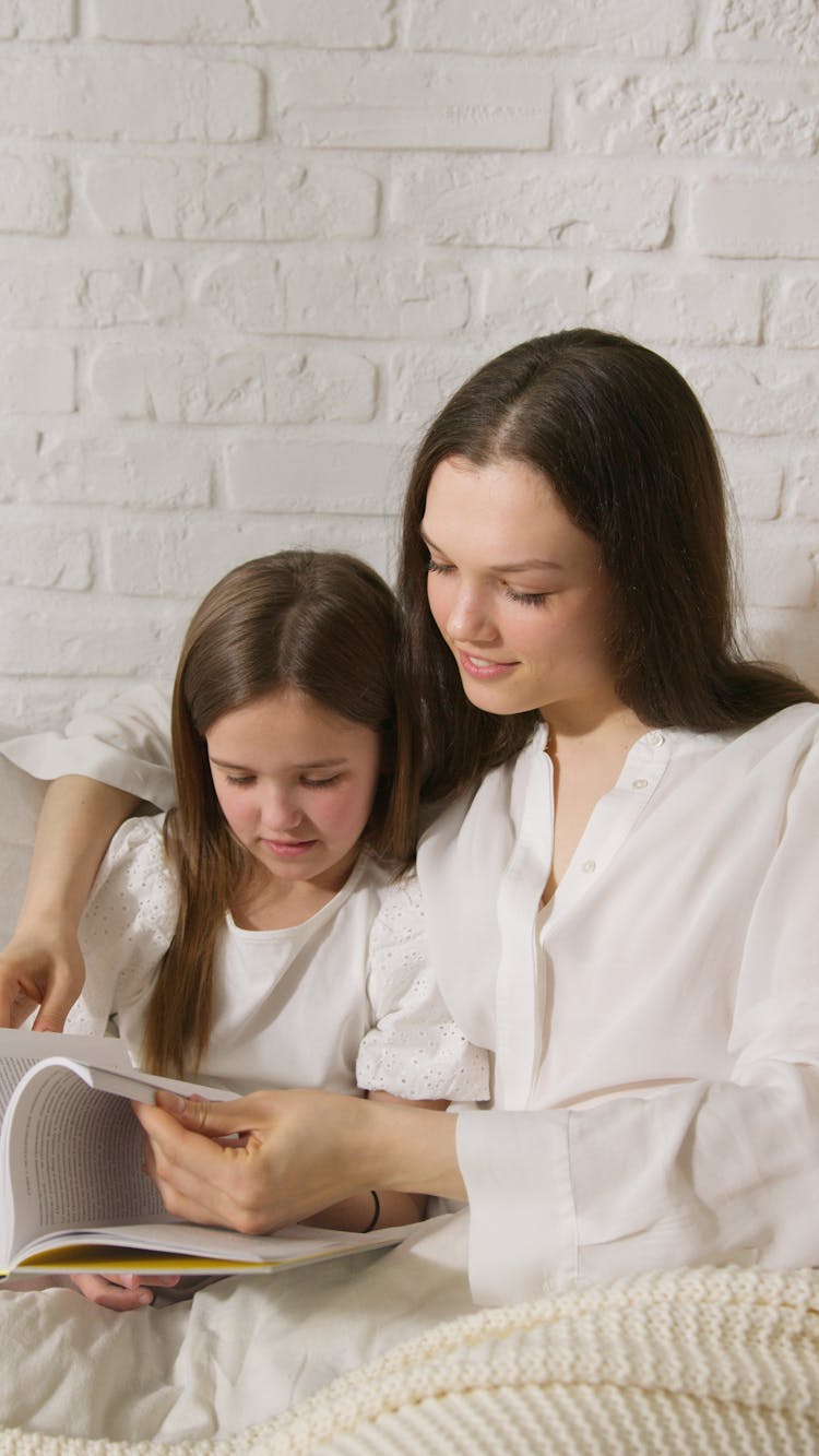 A Woman Reading A Book With Her Daughter 