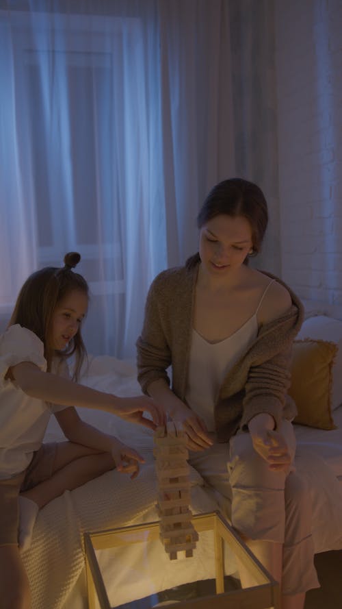 Mother and Daughter Playing Jenga in a Dark Room