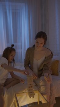 A mother and daughter enjoying a game of Jenga in a cozy indoor setting.