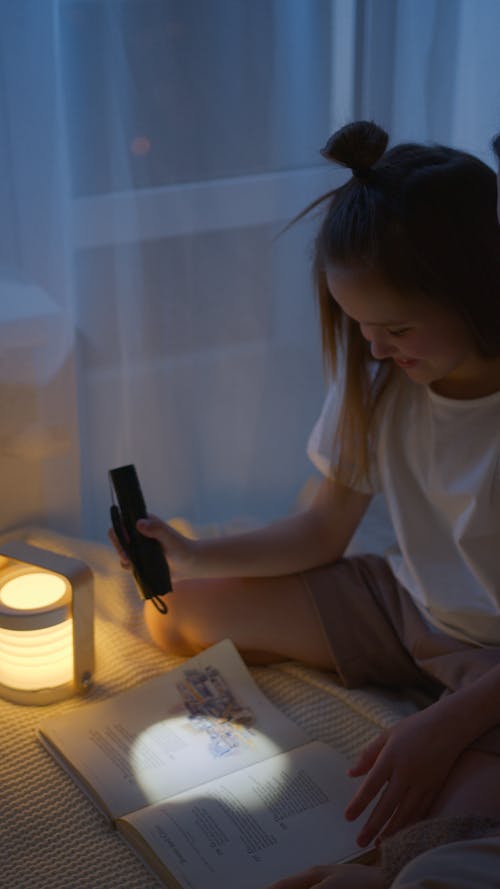 Free A Girl Reading a Book Using a Flashlight  Stock Photo