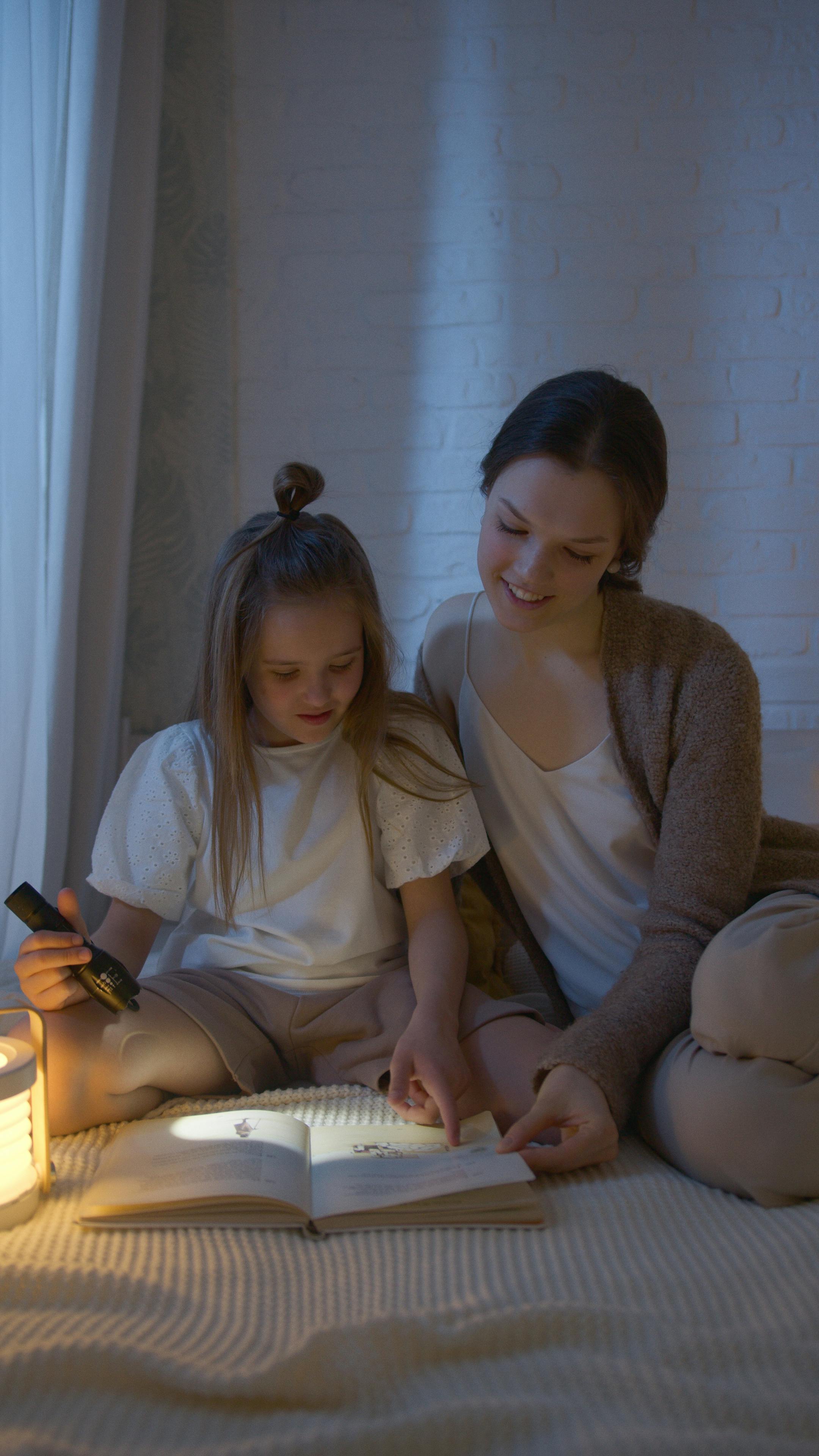 woman in white long sleeve shirt sitting beside girl in white long sleeve shirt