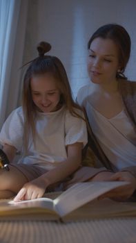 A mother and daughter share a tender moment reading books together at night.