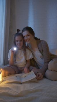 Mother and daughter sharing a bonding moment reading a bedtime story under soft light.