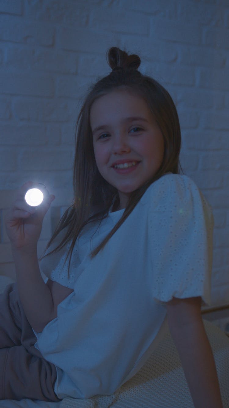 Smiling Girl In White Shirt Holding A Flashlight