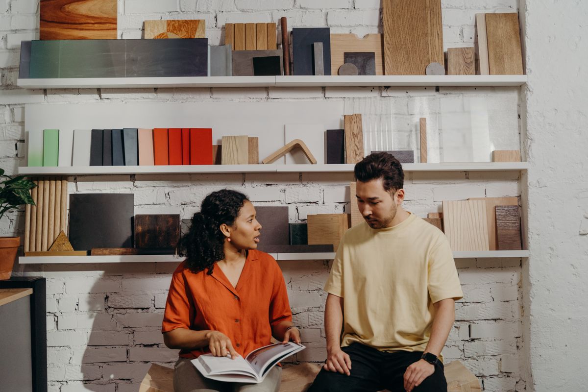 A woman pointing at a catalog while talking to a man in a showroom
