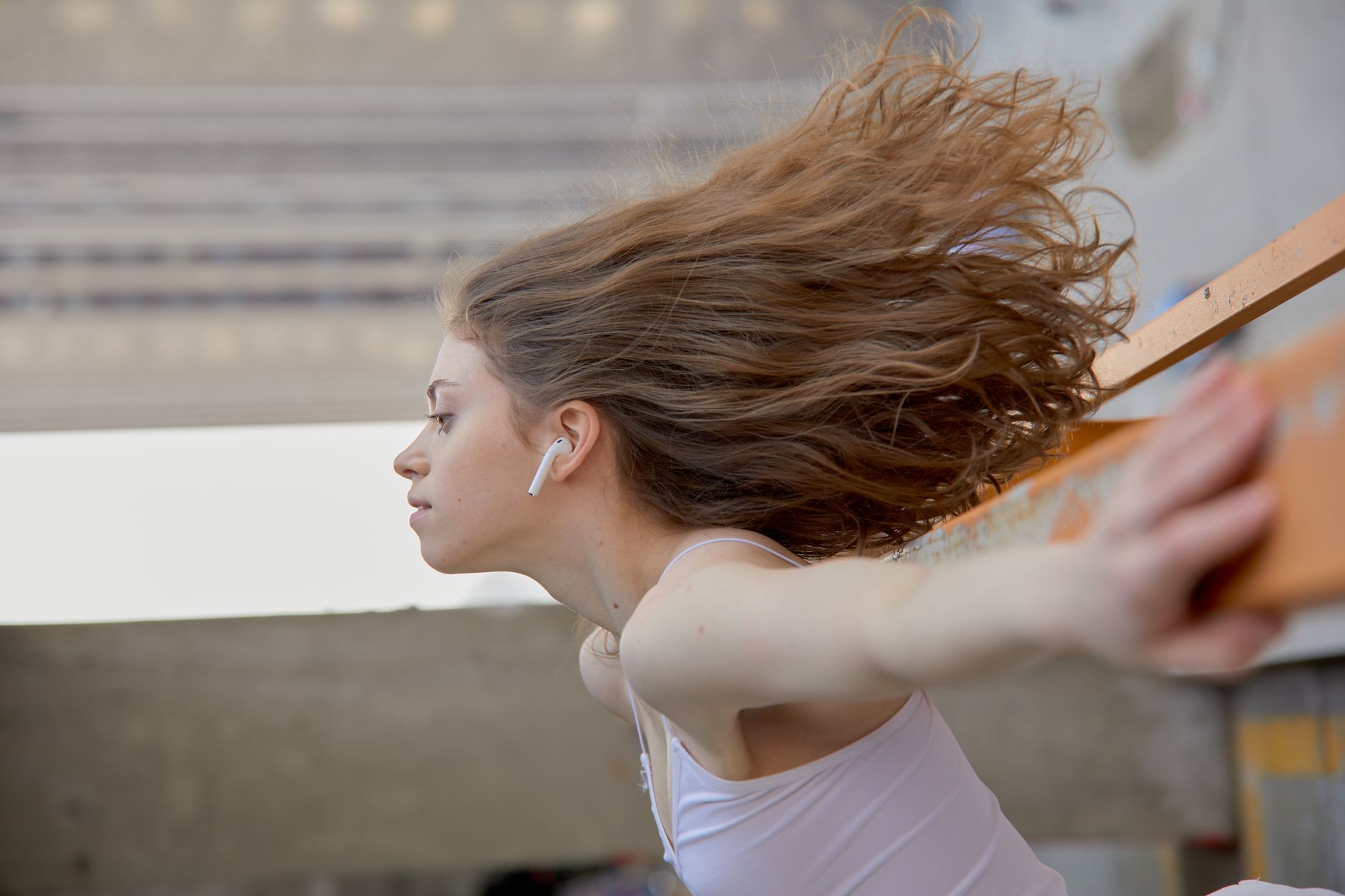 Captivating side view of a young woman wearing wireless earbuds, caught in motion.