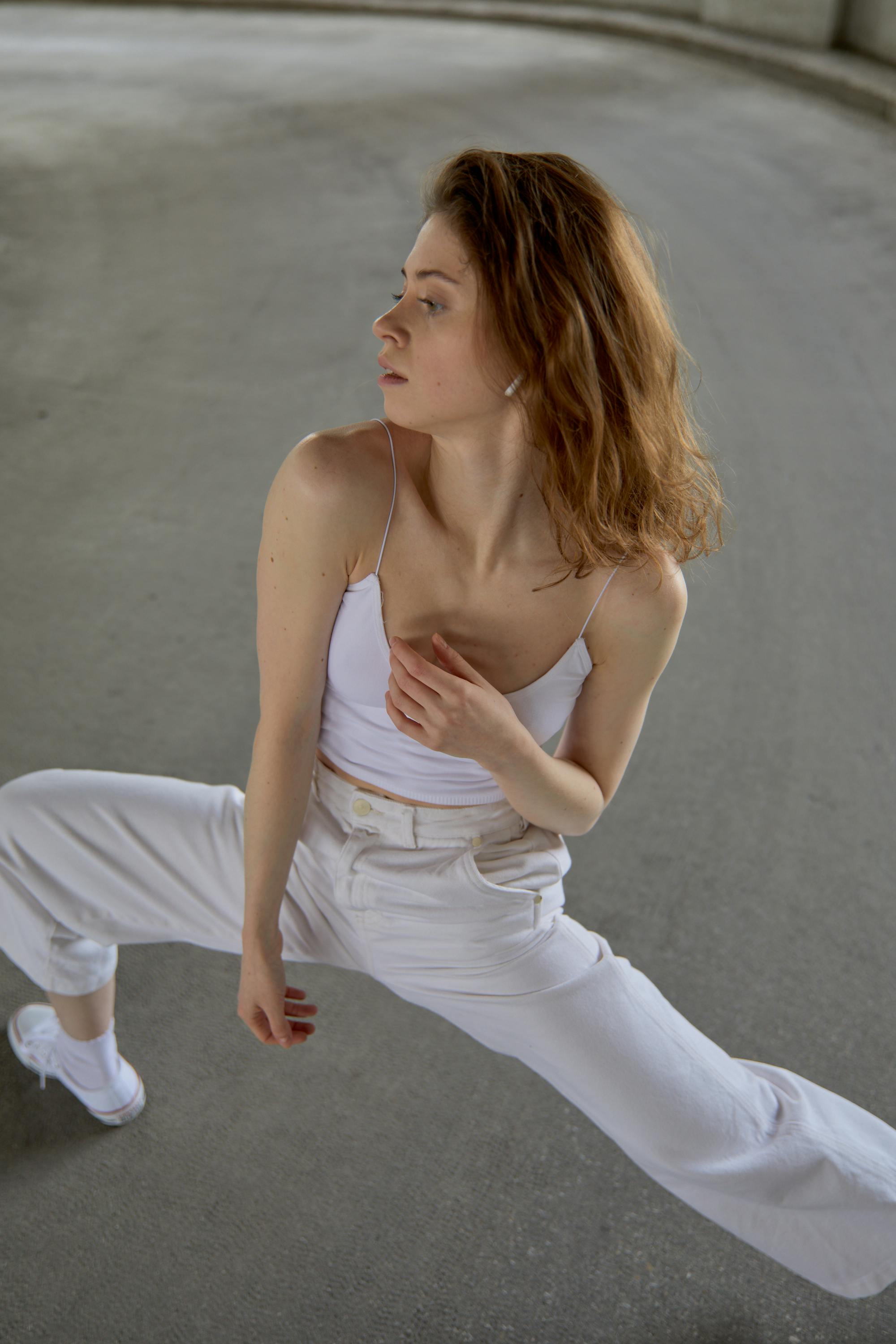 Caucasian woman elegantly stretching in a dance pose indoors.