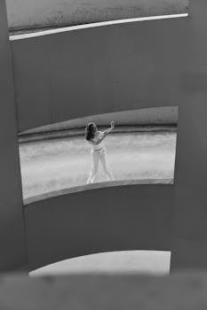 Artistic monochrome image of a woman dancing in an urban car park with geometric lines.