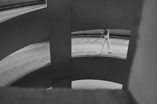 Grayscale Photo of Woman Dancing on Driveway of a Car Park