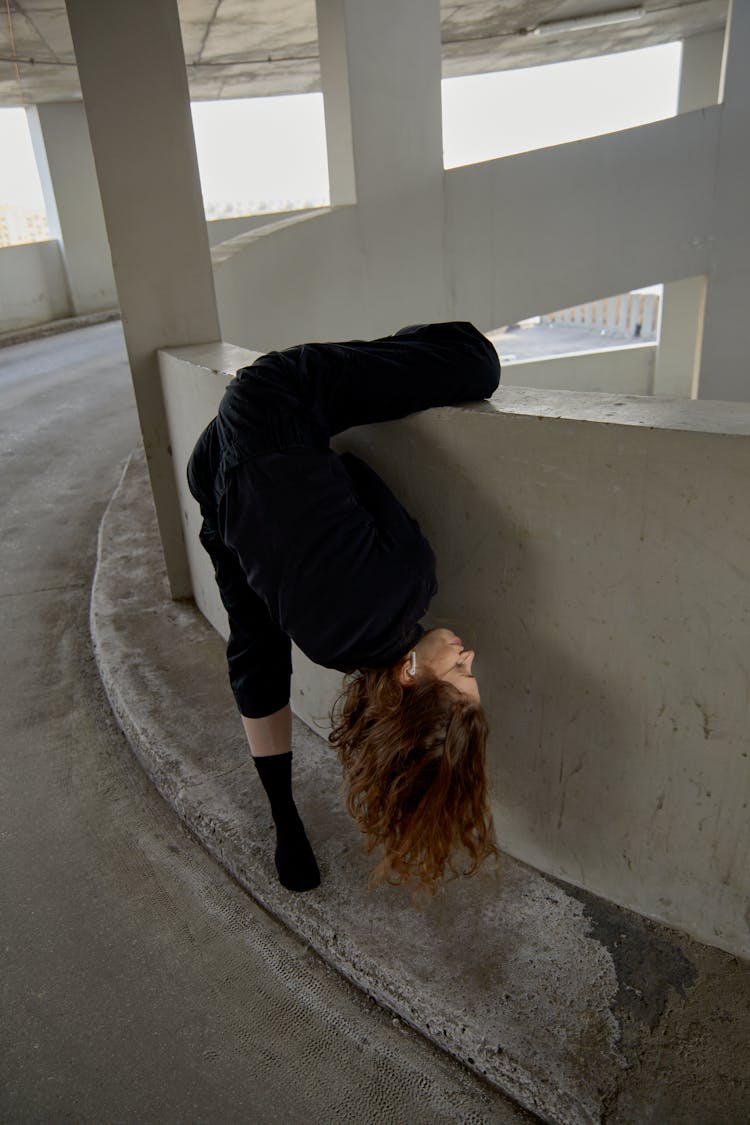 Woman In Black Coveralls Dancing Inside A Car Park