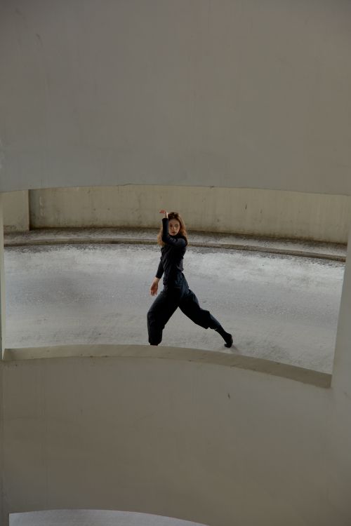 Free A woman dancing expressively in a modern parking garage. Stock Photo